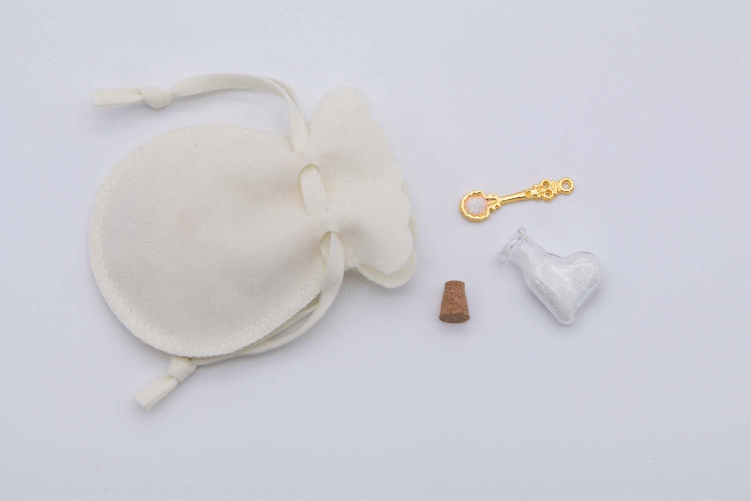 תיק קסם לפיה המתחילה – מתנה אישית לפיה המתחילה ומזכרת מיום הולדת פיות - תיק קטיפה לבנה 1 תיק קטיפה לבן עם בקבוקון זכוכית מיניאטורי בצורת לב עם נצנצים לבנים וכפית קסמים מיניאטורית – ערכה קסומה לפיה המתחילה ומתנה מקורית ליום הולדת בנות.